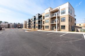 Greenville apartment for rent - A large parking lot in front of a multi-story apartment building.